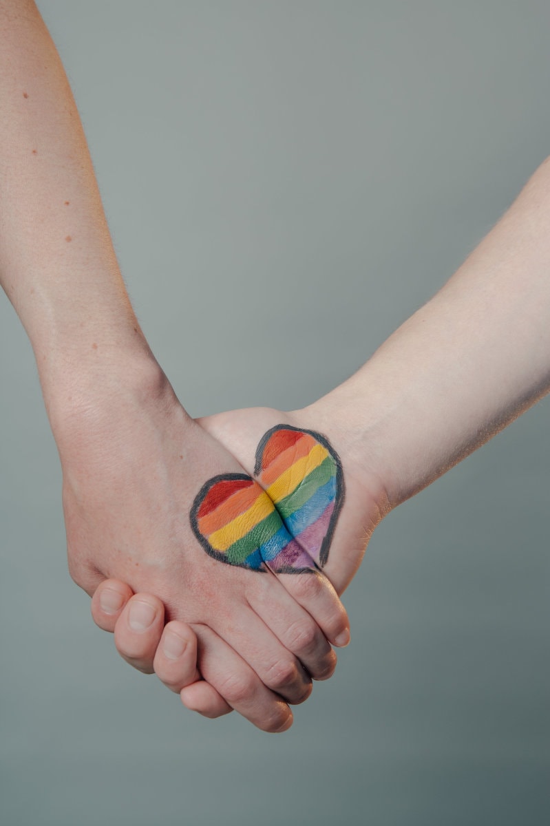 two hands being held with a rainbow heart painted on them