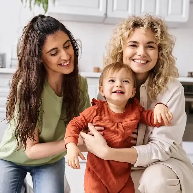 Two women holding and playing with a toddler.